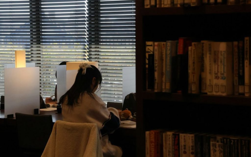 A quiet library reading room with long tables and shelves