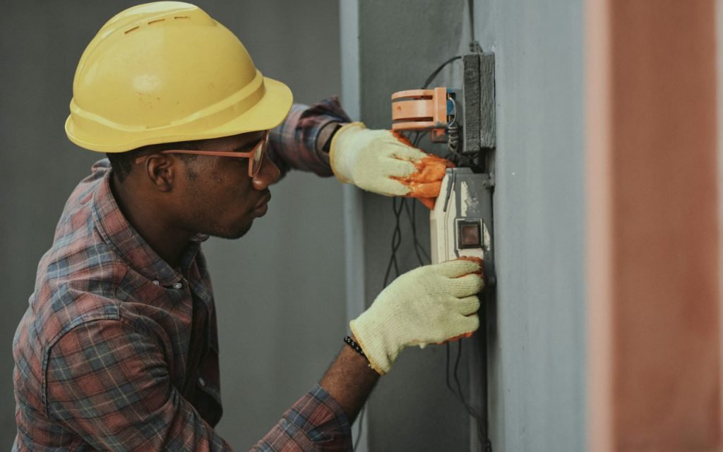 An electrician working on an open electrical panel
