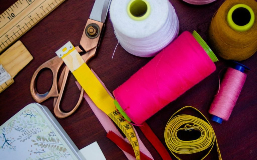 A tailor working with fabric and thread at a sewing table