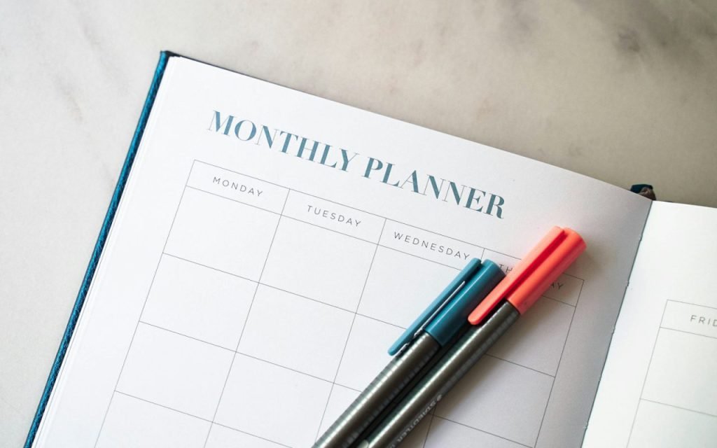 A monthly planner and pen on a desk for tracking bills