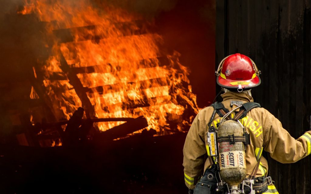 Firefighter in protective gear at the scene of a fire