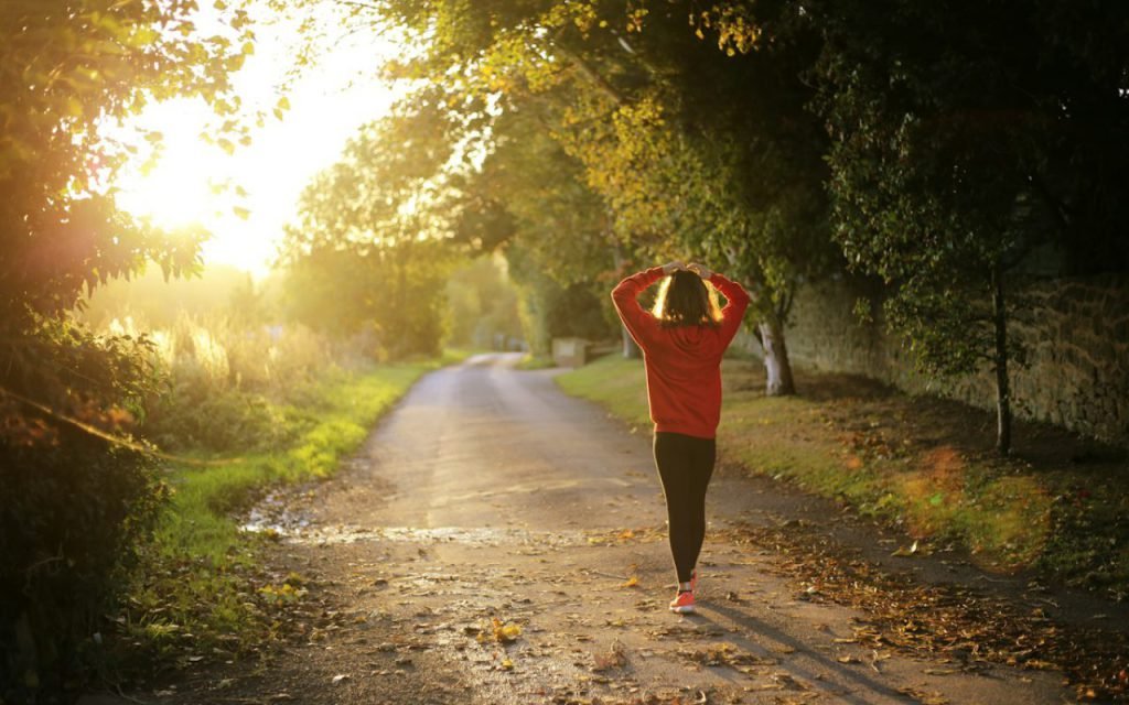 A woman walking on a tree-lined path in the early morning
