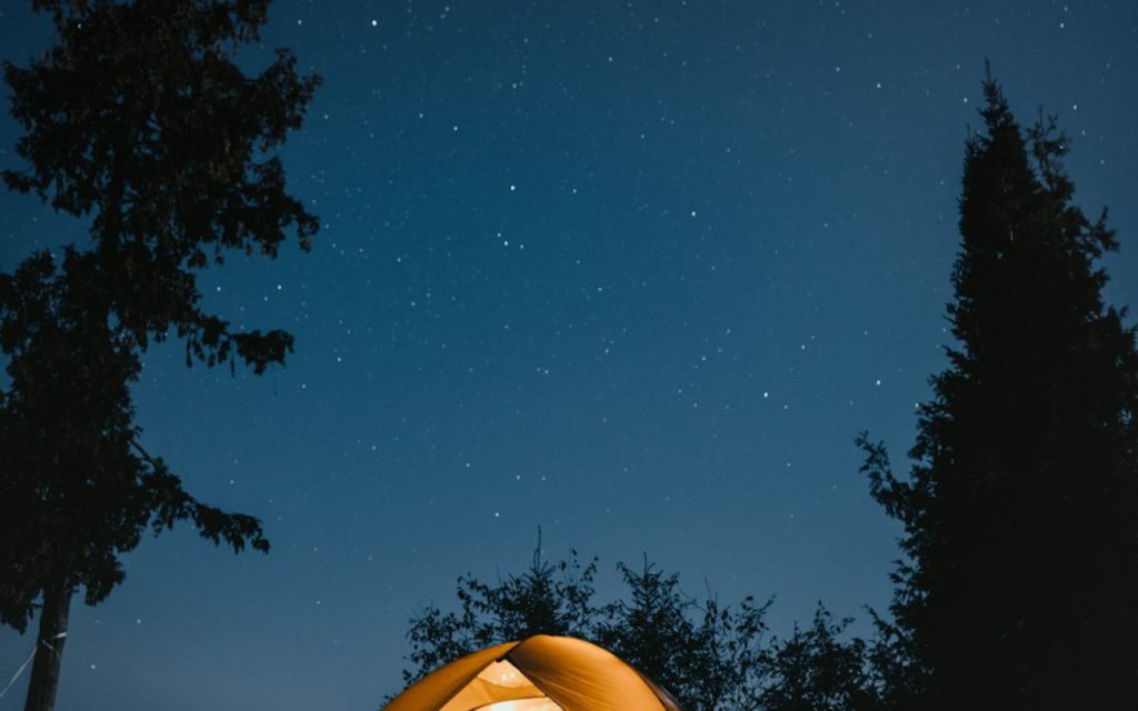 A tent glowing under a starry night sky