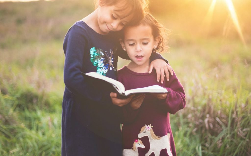 An adult and a young child reading a book together