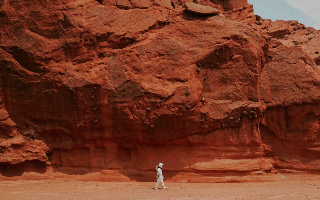 A rover-style explorer on a reddish rocky landscape