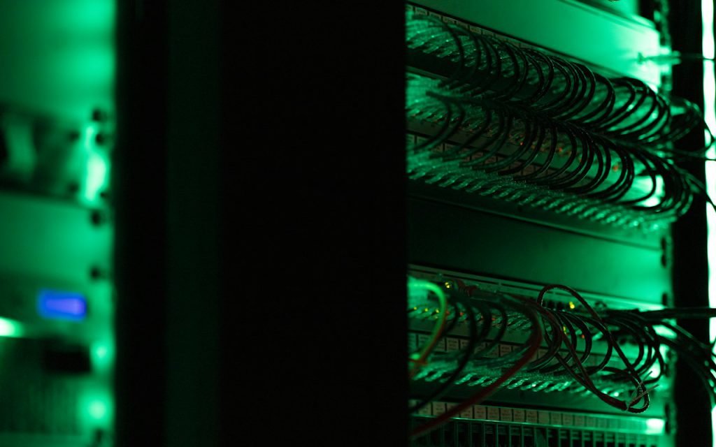 Rows of networking equipment glowing green in a server room